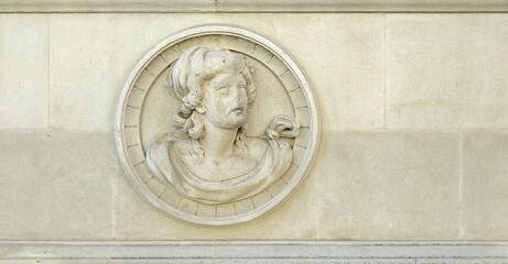 Ornament in white stone of a broken ancient relief on a wall which represents a profile portrait of a woman with frames with free space in the sides