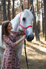 Obraz premium Young beautiful woman walking in the forest with her horse 