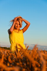 Happy womanin yellow dress in golden wheat