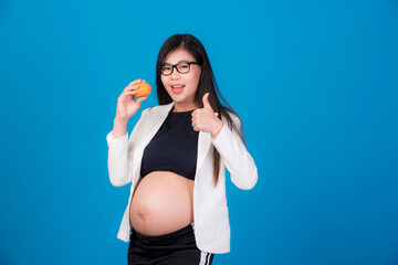 Beautiful pregnant woman in Asia is holding an orange in her hand. On a pink background, expectation of a young mother, pregnancy and childbirth pictures.