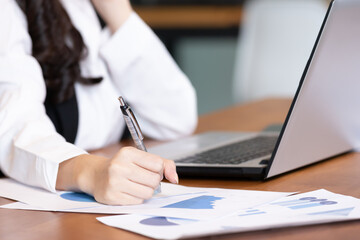 Asian business woman use labtop and note job on paper in office.