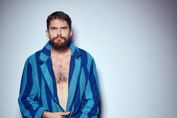 emotional man in a blue striped robe with a belt on a light background cropped view close-up