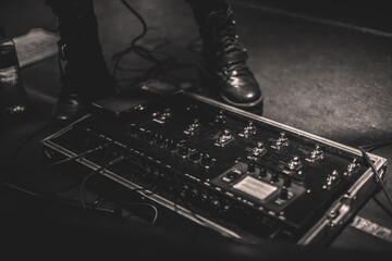 Guitar pedal and a pair of leather boots during a heavy metal show - Black and white photography - Powered by Adobe