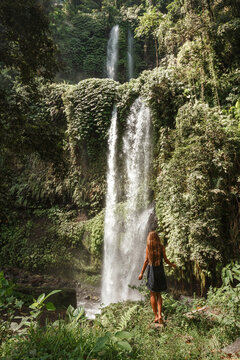 Young woman backpacker looking at the waterfall in jungles. Ecotourism concept image travel girl