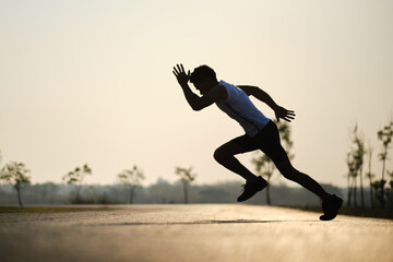 Silhouette young man jumping on the road during sun rise