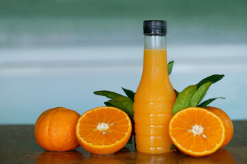 Oranges juice in bottle and fresh orange in the brown table which has dim light