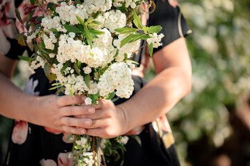 Woman wearing floral dress holding bunch of white flowers in beautiful cottage garden
