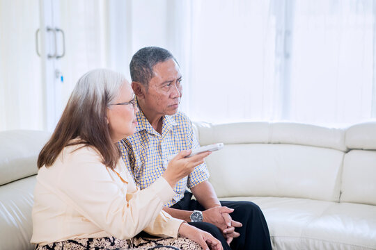 Side View Of Elderly Couple Watching TV At Home