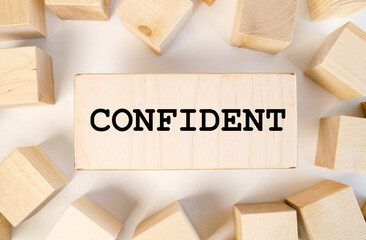 confident, text on a piece of wood on a light background.