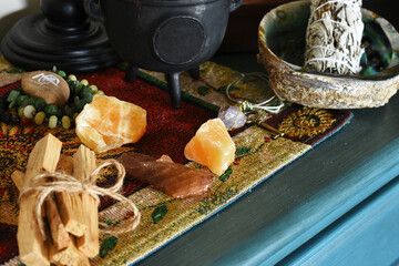 An image of several palo santo smudge sticks with yellow calcite crystals on a blue table top. 