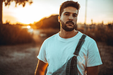 Chico joven vistiendo un mono vaquero con atardecer puesta de sol en el sur de españa modelo