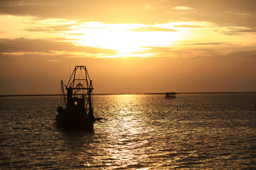 Fototapeta na wymiar Silhouette Fisherman boat againt sunset or sunrise at Chonburi, Thailand