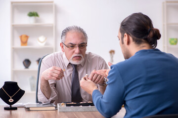 Young man visiting old male jeweler