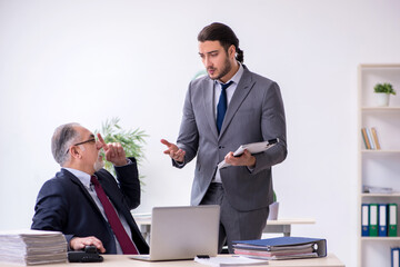 Old boss and his young assistant working in the office