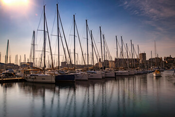 Fototapeta na wymiar Sailboats in the port of La Canebière with their reflections at sunset - Marseille - France - June 2019