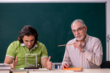 Old professor physicist and young student in the classroom