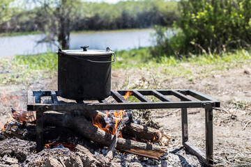 Cooking fish soup in a pot over a fire. Field kitchen. Hike. Camp in the woods.