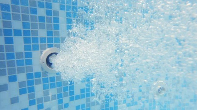 Underwater Bubbles from jacuzzi water jet in thermal spa pool. With blue tiles, slow motion