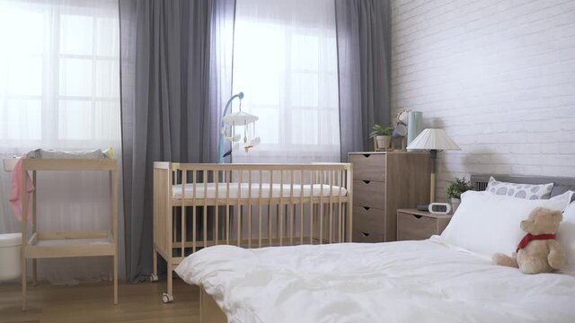 panoramic view of a contemporary bright organized bedroom equipped with a baby bed and a diaper change.