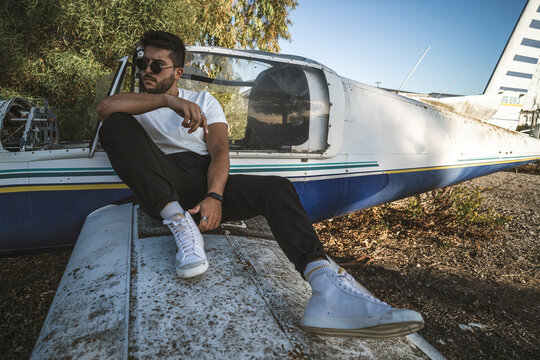 Hombre Joven con camisa de cuadros posando en una avioneta abandonada. Modelo