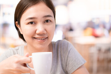 Beautiful Asian woman enjoy drinking a coffee in cafe.