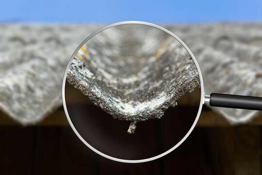 Old and very dangerous asbestos roof. Asbestos dust in the environment. Health problems. View through magnifying glass