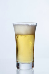 白い壁を背景に透明なグラスに入った冷えたビール