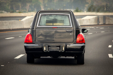 A black hearse driving down a freeway - obrazy, fototapety, plakaty