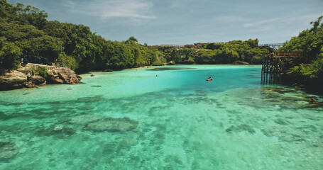 Closeup people swim at turquoise crystal clean water of Weekuri lake. Tourists landmark in green...