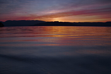 Fototapeta na wymiar 夕暮れの湖。徐々に暗くなって行く日没の風景。