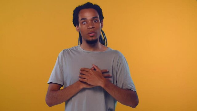 Emotional attractive African American male with opened mouth expresses great surprisment and frightens, poses against orange background, stares at camera. Unexpected shocking news and human reaction
