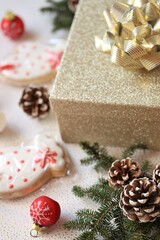 Fototapeta na wymiar Christmas presents.Gift gold box, Christmas cookies, red balls, fir cones on a light background.Surprises and gifts for Christmas and New Year. Winter holidays time.buying new year gifts