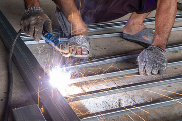 The welder is welding the parts of the iron door. The person working on a welder using an electric welding machine.