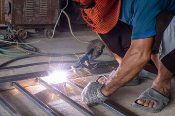 The welder is welding the parts of the iron door. The person working on a welder using an electric welding machine.