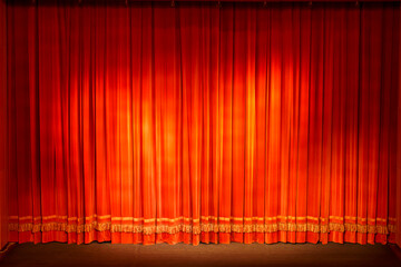 Closed theater curtain, red and gold, illuminated by devices.