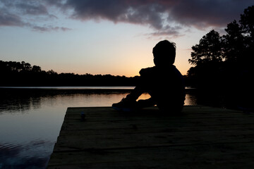 CHILD IN THE SUNSET OF A LAKE
