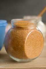 Preparing to bake sweets for a birthday party. Isolated jar cane sugar. In the background a glass with flour, a mixer and a plastic bowl