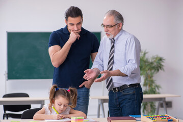 Young parent, old male teacher and little girl in the classroom