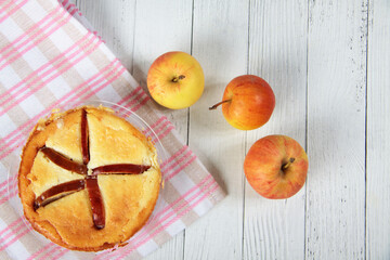 curd apple pudding and apples on napkin on white wooden background flat lay. Horizontal image