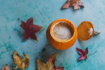 Fototapeta na wymiar pumpkin spice latte on turquoise background with fall leaves