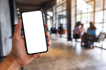 Mockup image of a man holding black mobile phone with blank white screen in cafe