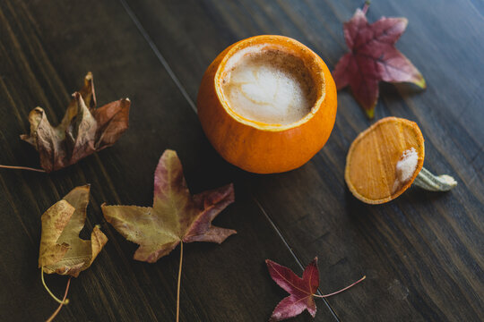 autumn leaves on wooden table with pumpkin drink