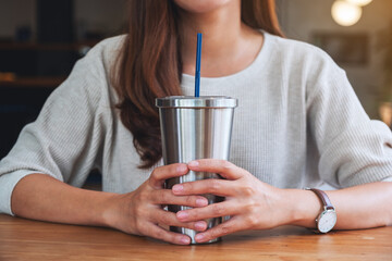Closeup image of a beautiful asian woman drinking coffee in stainless steel cup