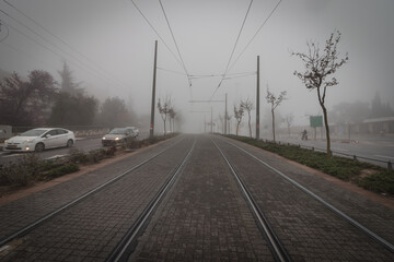 The railroad tracks of the light rail in Jerusalem are covered in fog, on a rainy winter day.