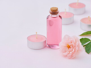 Obraz na płótnie Canvas Aromatherapy oil bottle and pink rose
