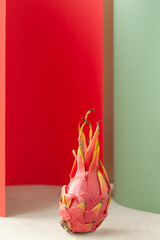 vertical image ripe red juicy dragon fruit pitaya between rolls of red and green pastel paper rolls, food geometry trend, selective focus