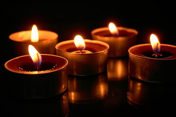 Fototapeta na wymiar Burning candles on a black background, selective focus, romantic setting, romantic atmosphere, shot with shallow depth of field.