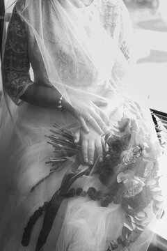 Cropped vintage black and white image of a bride with a bouquet in her hands under a veil.