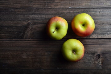 three red apples on brown rustic wooden background, top view, copy space