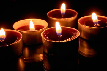 Burning candles on a black background, selective focus, romantic setting, romantic atmosphere, shot with shallow depth of field.